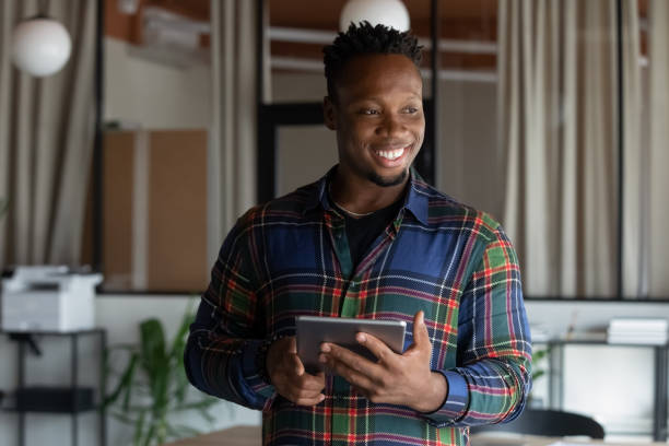 istock Joyful young dreamy african employee using digital tablet. 1416019246