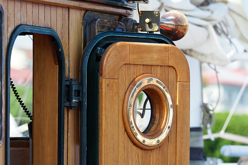 Wooden entrance in the wheelhouse cabin with porthole of an old fishing schooner
