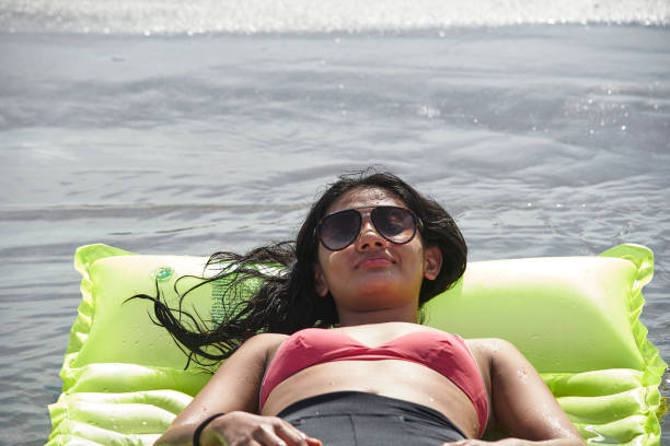 young latin woman resting on the beach on a green inflatable beach toy