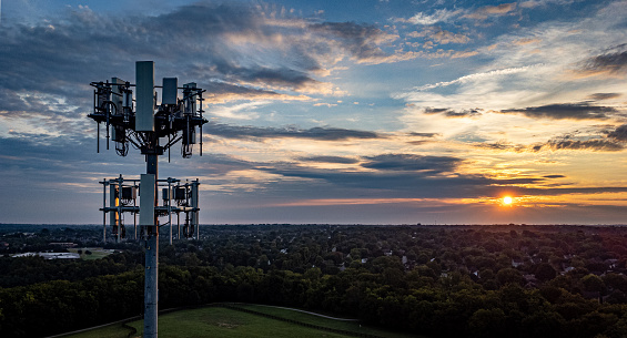 Cell phone tower on the foreground, neighborhoods of Lexington, Kentucky on a distance during early morning sunrise.