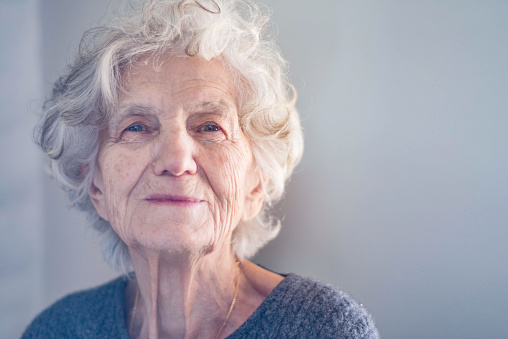 Senior grey-haired woman wearing striped navy t-shirt glasses over isolated white background smiling looking to the side and staring away thinking.