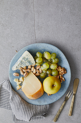 Tapas with blue cheese, parmesan, apple, pistachio, nuts and grapes, on a gray granite table, with a space for copy