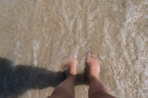 Close up of woman's legs standing in the sea