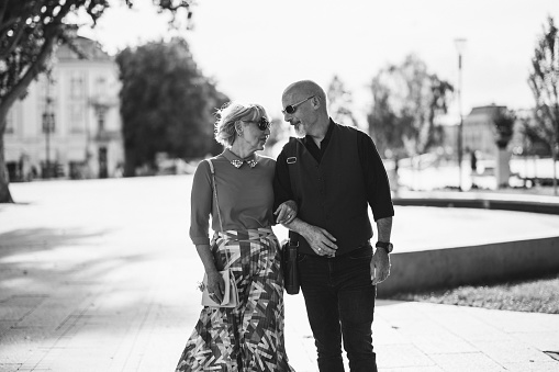 Man and woman, happy mature couple taking a walk outdoors in city. Black and white.