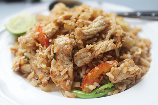 Close up fried rice with pork and vegetables on the white dish.