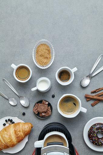 Morning espresso cups art serving, on a modern gray table with croissant and chocolate, top view with a free space for a copy