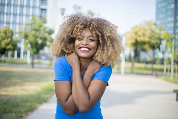 Attractive African American Woman Outdoors In Bare Shoulder Dress And Braided Hair Smiling