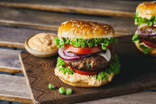cheeseburger su un tagliere di legno fatto in casa con uno sfondo scuro - food vegan food gourmet vegetarian food foto e immagini stock