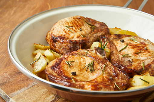 Tasty beef stakes in a pan with baked potato and spinach, on a home or restaurant kitchen table