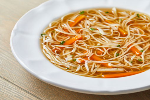 Homemade close up of a vegetable soup, on a light wooden kitchen table top
