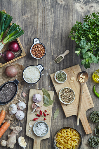Fresh vegan ingredients, vegetables, herbs, spices and seasoning on a kitchen wooden table top, top view