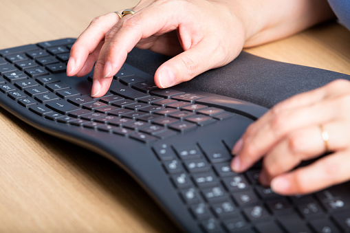 Details of woman's hands texting on a keyboard