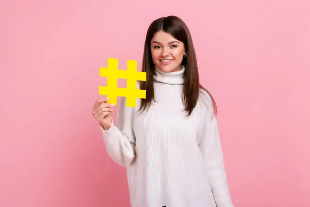 Photo of Beautiful woman holding hashtag symbol, promoting viral topic in social network, tagging blog trends