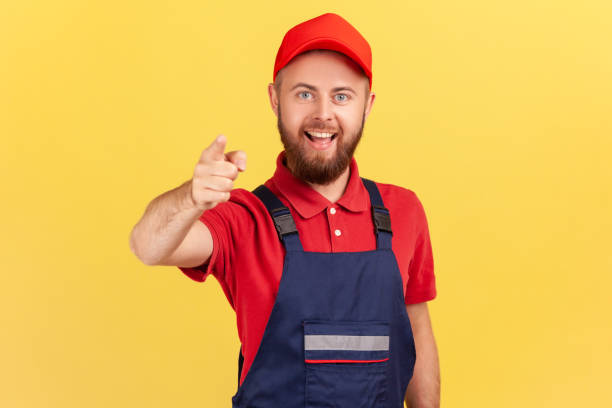 istock Smiling bearded satisfied man worker standing and pointing finger to camera, choosing you. 1416037868
