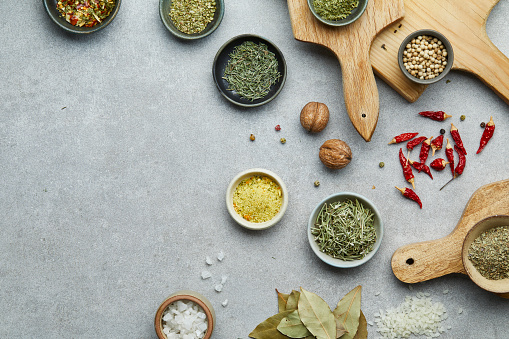 Spice and seasoning in a small handmade ceramic bowls, on a wooden cutting boards, on a gray granite table top, top view concept with a large copy space for text