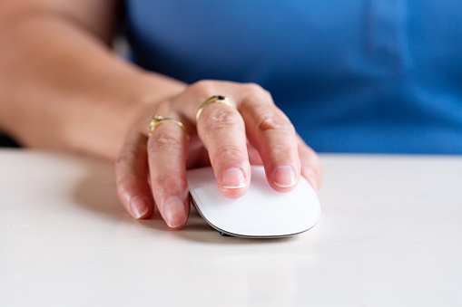 Details of woman's hands working using a mouse on a desktop