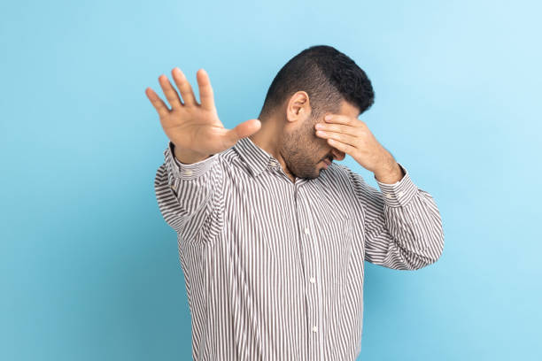 hombre de negocios cerrando los ojos con la palma de la mano, extendiendo otra mano hacia adelante tocando el espacio. - hiding fear business men fotografías e imágenes de stock