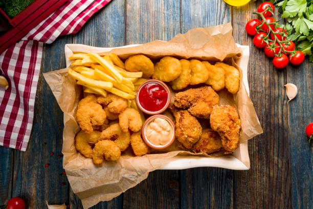 assorted beer snacks, chicken nuggets, french fries, shrimps temputa and chicken wings top view assorted beer snacks, chicken nuggets, french fries, shrimps temputa and chicken wings top view chicken balls stock pictures, royalty-free photos & images