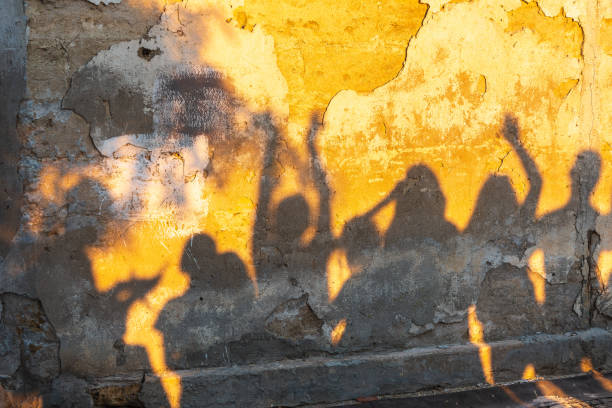 istock Shadows of dancing people on an old stone wall at sunset time. 1416040407