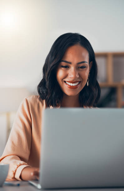 istock African woman working on laptop, networking on social media online and browsing internet while sitting in an office alone at work. Smiling and cheerful female manager planning and creating a strategy 1416049295