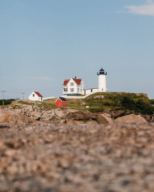 маяк на мысе неддик на мысе неддик, йорк, штат мэн - flag maine nubble lighthouse vertical стоковые фото и изображения