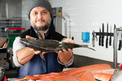 Happy and exctied mature fisherman holding a big carp fish isolated on white background