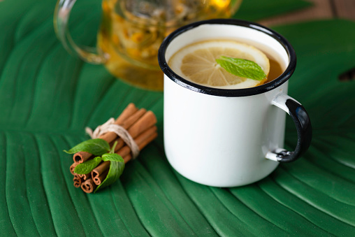 Herbal tea with lemon slice  with chamomile plants and cinnamon.