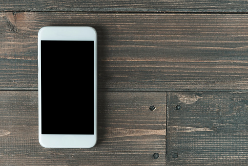 Directly above view of a smart phone over a wooden background.
