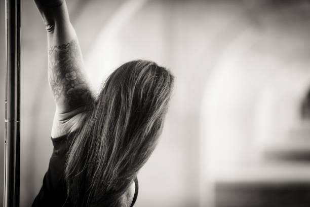Caucasian middle aged female pole dancer outside White female pole dancer on a stage pole outdoor under a highway overpass with arched supports and lots of concrete. black pole dancers stock pictures, royalty-free photos & images