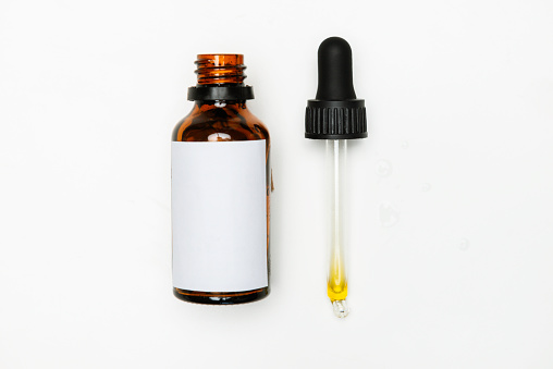 Bottle of beauty serum with pipette on pure white background.