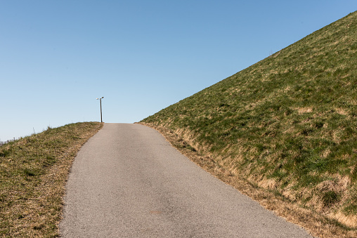 Steep uphill road with grass fields on each side.