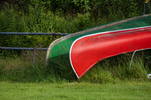 Green and red canoes in storage near a lake.