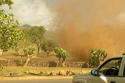 A rare dust devil forms over the southeast coast of Maui island Hawaii on November 1 2007. Dust devils common on the plains of the lower 48 states are unusual on the islands. They form as a result of very unstable air in the lowest portions of the atmosphere but are not associated with convective clouds as with a waterspout or tornado. The spin also develops from the ground on up through a column of air. In this instance the reddish brown volcanic soil makes for the colorful whirlwind.