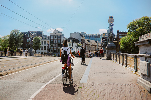 Woman cycling in Amsterdam, commuting or just sightseeing on a bright summer day.