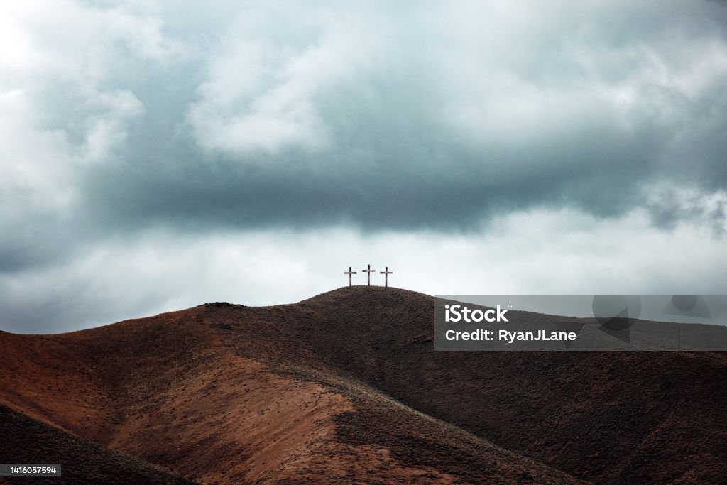 Three Crosses on Dark Hillside A depiction of the Easter story, three crucifixes line the top of a barren gloomy hill.  A crucial point in Christian history. Religious Cross Stock Photo