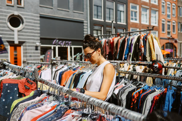 shopping in the Amsterdam open market Woman looking through the Amsterdam outdoors vintage market, shopping for vintage clothing. second hand stock pictures, royalty-free photos & images