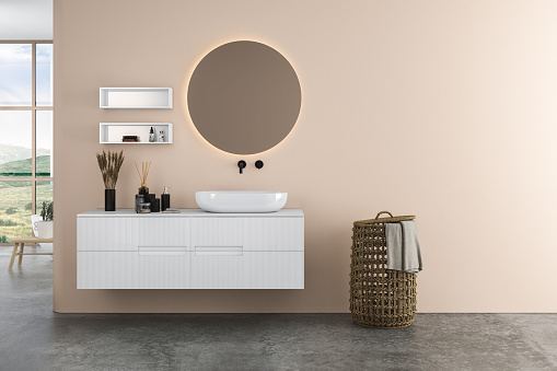 Modern bathroom interior with beige walls, ceramic basin with oval  mirror, bathtub and grey concrete floor. Minimalist beige bathroom with modern furniture. 3D rendering