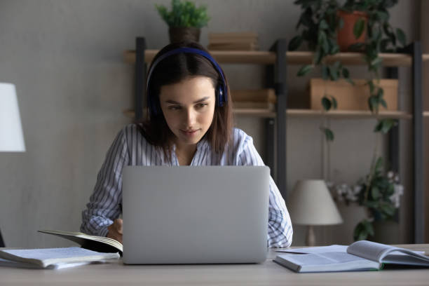 istock Happy young woman in headphones watching educational lecture on computer. 1416065717