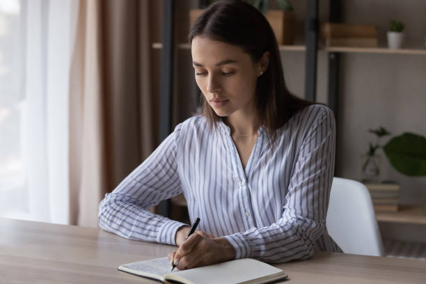 istock Concentrated smart young business lady making notes in planner. 1416065735