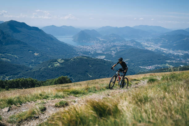 istock Athlete rides e-mountain bike on trail above mountains 1416065805