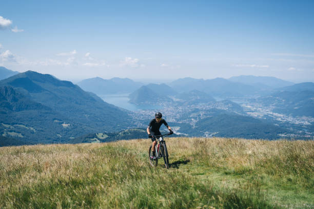 istock Athlete rides e-mountain bike on trail above mountains 1416065824
