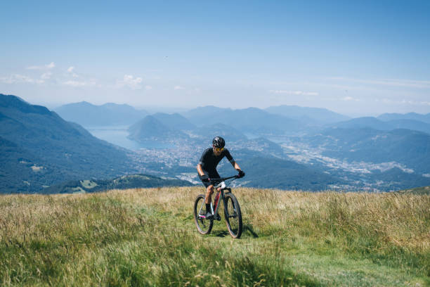 istock Athlete rides e-mountain bike on trail above mountains 1416065856