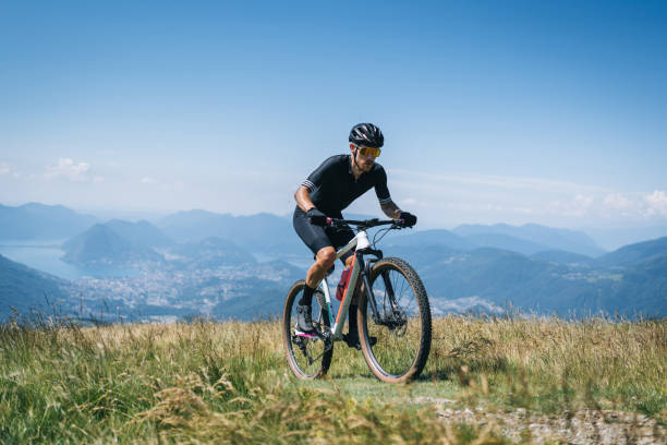 istock Athlete rides e-mountain bike on trail above mountains 1416065862