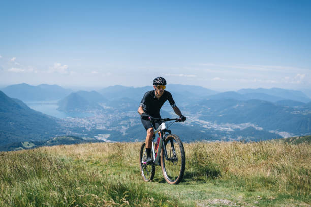 istock Athlete rides e-mountain bike on trail above mountains 1416065863