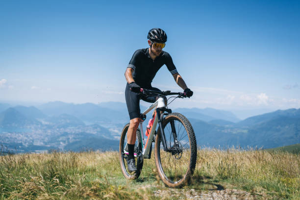 istock Athlete rides e-mountain bike on trail above mountains 1416065878