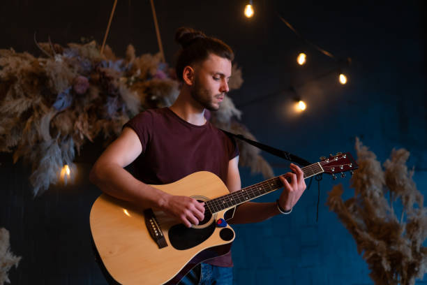 male musician playing acoustic guitar. guitarist plays classical guitar on stage in concert - men artist guitarist guitar imagens e fotografias de stock