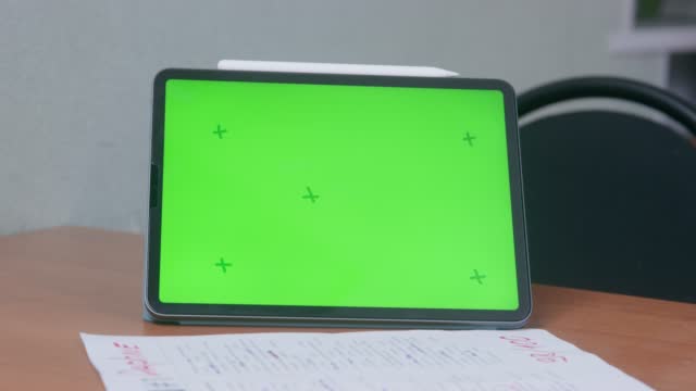 Document, digital pencil and tablet with chromakey screen are on table