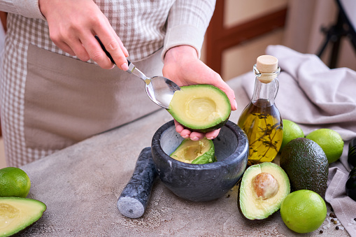 Closeup on hands holding fresh avocado cut in half making guacamole.