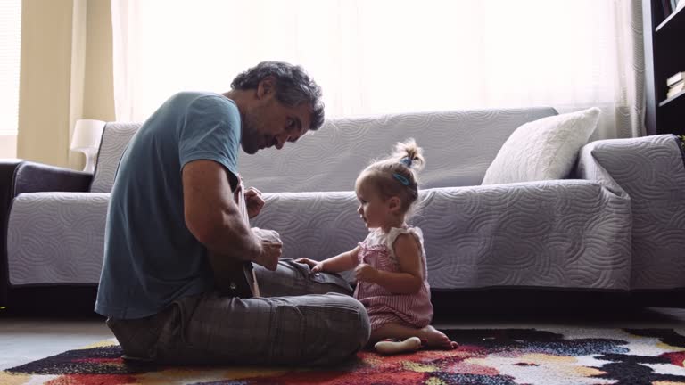 Father plays the guitar to his daughter at home.