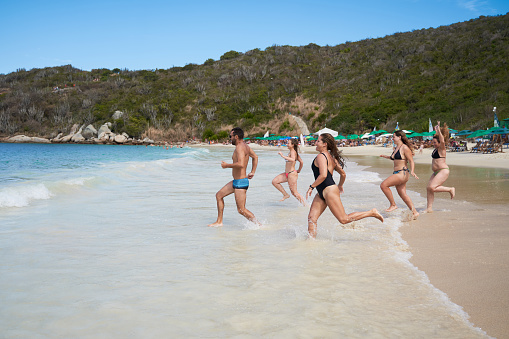 Group of people running towards the sea on the Praia do forno (oven beach), Brazil